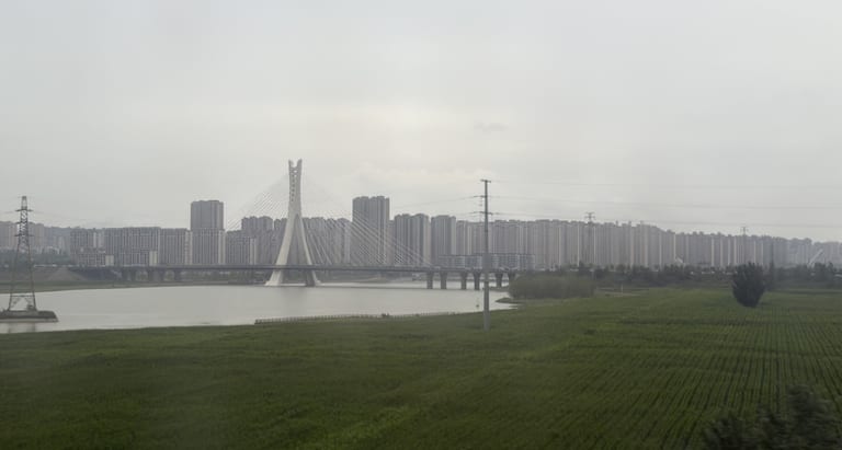 途经大同市平城区附近的一座斜拉桥跨过河流，背景是连片的现代住宅楼
