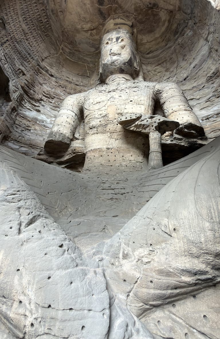 第十七窟内的立佛仰视,右臂已断,全身遍布凿孔与风化痕迹