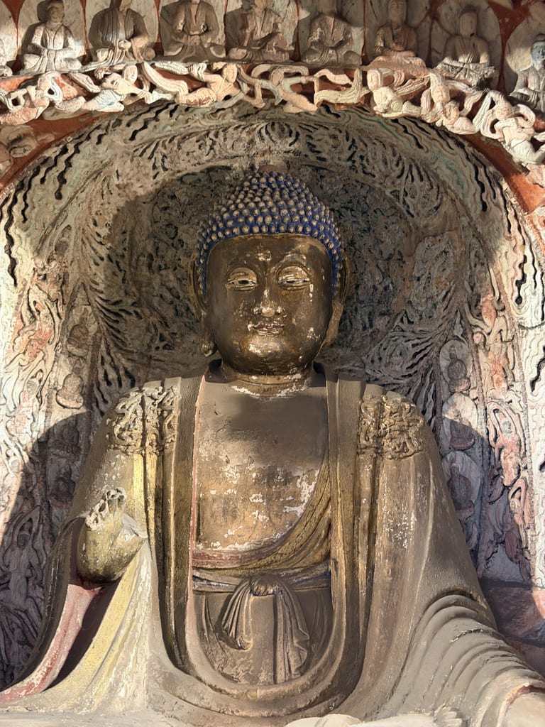 第五窟主佛,蓝顶发髻,彩绘袈裟,身后火焰纹背光,顶部一排小佛